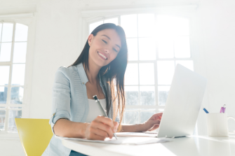 Happy Latin American woman paying bills online at home using a laptop computer
