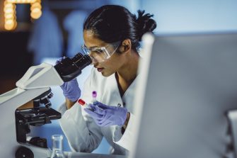 Biomedical engineer looking through a microscope in a lab