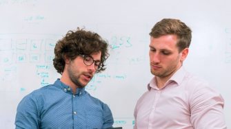 male engineers having discussion in front of whiteboard