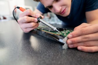 Close-up on an engineering student working on a robot and welding circuits
