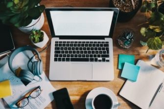 top view of work station with laptop, coffee, notebook