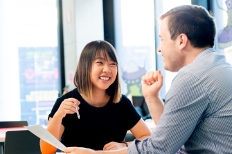 Photograph of a conversation between two adults discussing the disability inclusion plan
