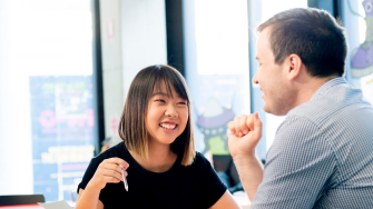 Photograph of a conversation between two adults discussing the disability inclusion plan