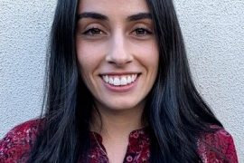 A headshot of Ella Werman smiling against a white wall