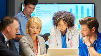 a mixed group of healthcare professional and business people meet around a conference table .