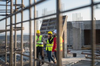 Construction workers standing on outdoor construction site and discuss the building plans