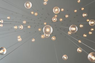 Lightbulbs are suspended from a ceiling. The photograph captures a low profile view of the bulbs from underneath. 
