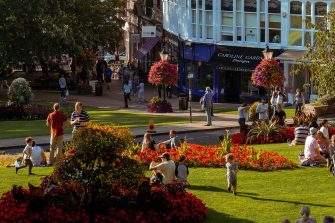 students sitting on park lawn in small town