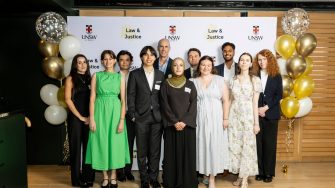 A happy group of people standing between gold balloons