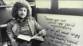 Young David Brown reading a book next to a poster with a quote on it
