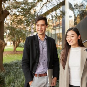 Law student couple standing together in front of Law Building, trees and greenary in background