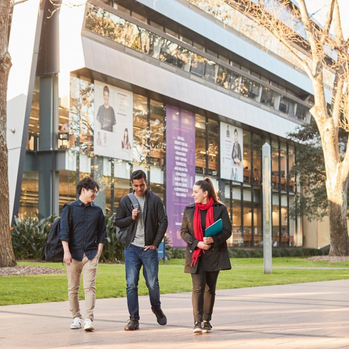 Three Law students walking on Main Wallkway with the Law Building in the background