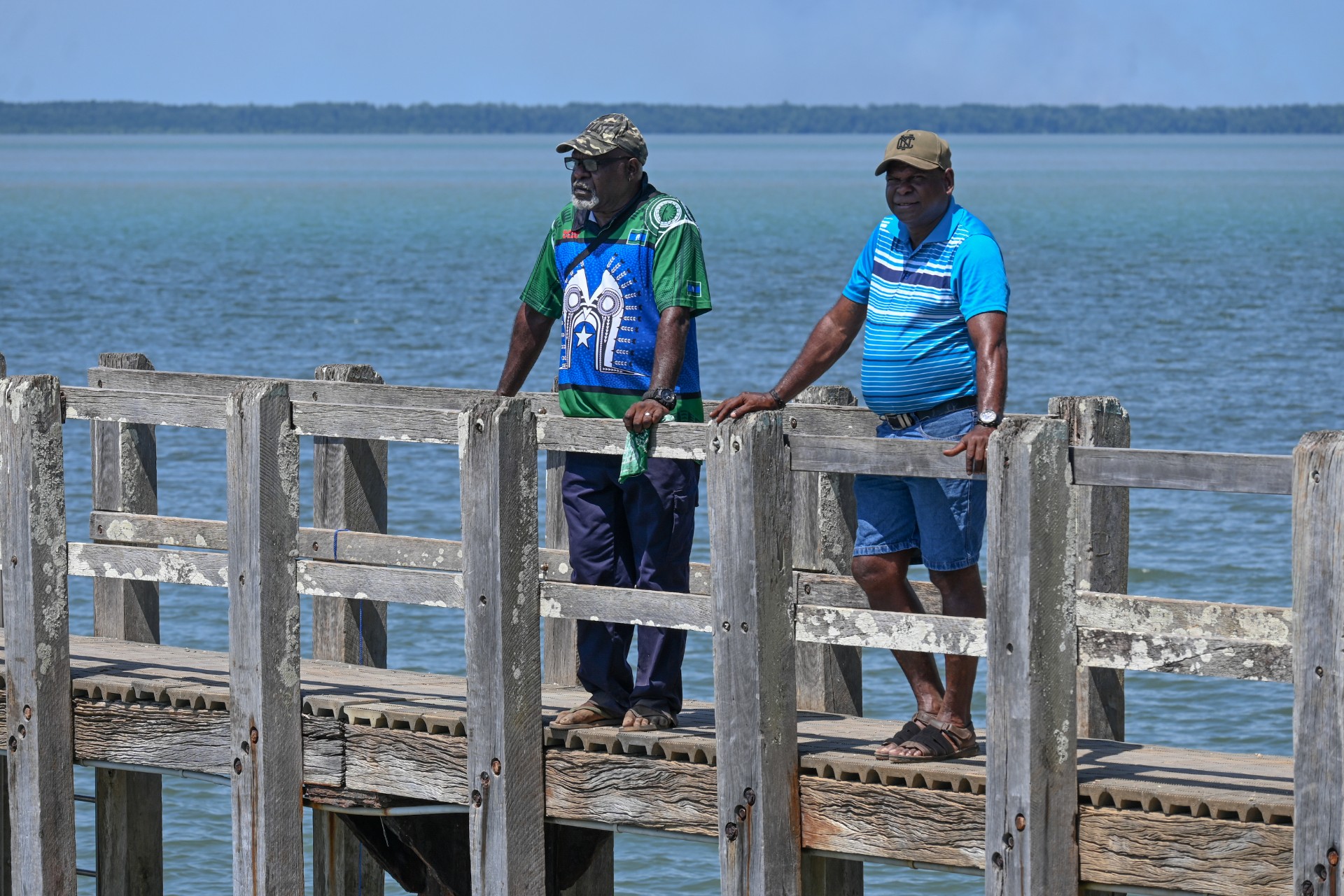 Two men on boardwalk looking out to ocean.