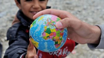Member of Ismail Ibrahim's family with a ball decorated as a globe that has been received at the  Vinojug Reception Center just inside the Macedonian border from Greece. ; 80 year-old Ismail and his extended family fled from northeast Syria 4 years ago, at the beginning of the war. They fled to Turkey where they tried to live a normal life, but they were unable to pay rent of a two-bedroom house. They had no choice but to risk their lives again.  This time to Europe. After crossing the Mediterranean Sea from Turkey to Greece, Ismail leads 23 family members, three generations of his family, mainly his daughters, his sons-in-law and grandchildren to safety, hoping to go to Germany.From January 1st to September 28, 2015, 520,957 refugees and migrants have arrived on European Mediterranean shores, 80 per cent of whom originate from the world’s top 10 refugee-producing countries. Over 50 per cent of the new arrivals are Syrians.  387,520 refugees and migrants land on Greek shores in hopes to continue their journey through the Balkan countries to Austria, Germany or Sweden.  Tragically, 2,980 migrants and refugees have lost their lives attempting to find safety in the European Union.