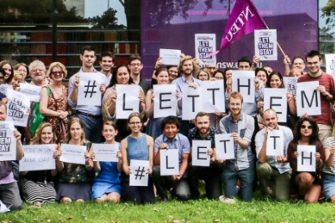 Large crowd of people holding let them stay signs