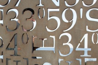 Image with coordinaets cut into a wall overlooking the ocean