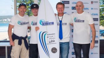 Tony Abbott posing with 3 others with a surf board in the middle