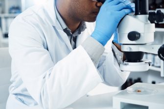Man, scientist and microscope, analysis in laboratory and check DNA sample with science experiment. Male doctor analyze data in lab, scientific innovation for development and medical research.