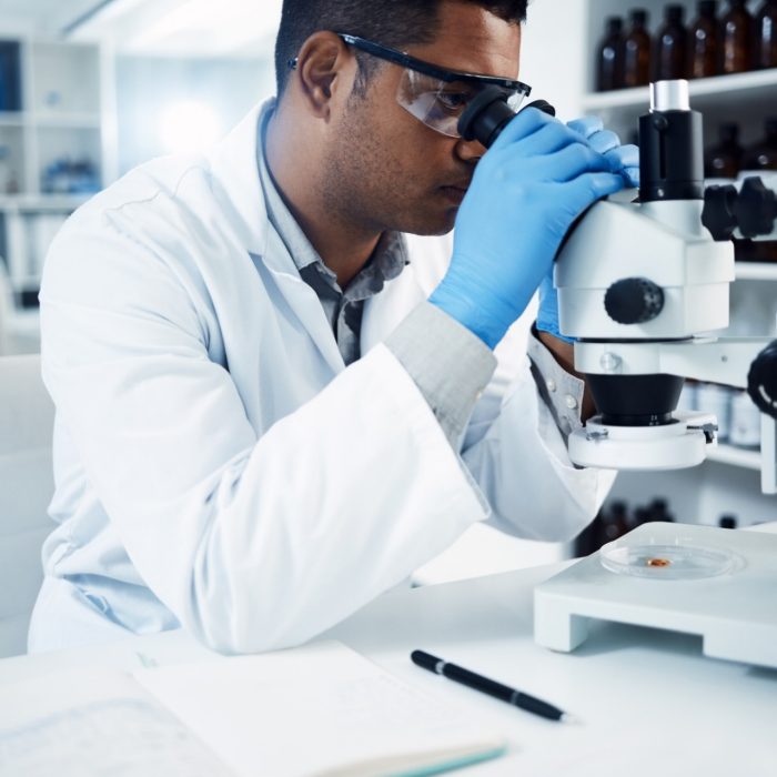 Man, scientist and microscope, analysis in laboratory and check DNA sample with science experiment. Male doctor analyze data in lab, scientific innovation for development and medical research.