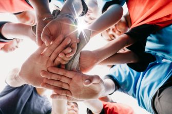 Low angle view of kids putting hands together in circle