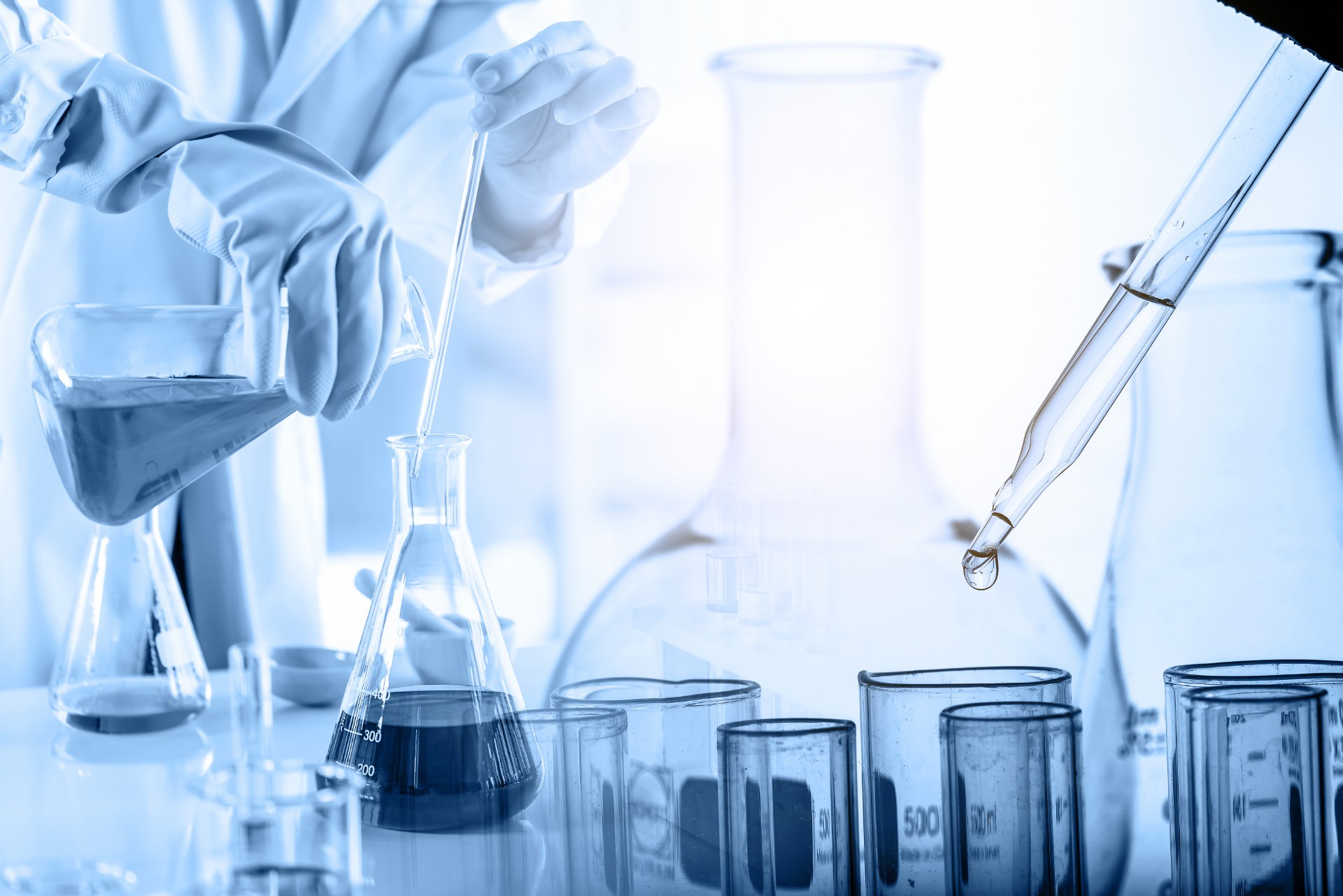 hand of scientist holding flask with lab glassware and test tubes in chemical laboratory background, science laboratory research and development concept