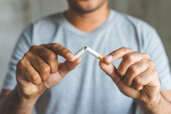 A man breaks a cigarette after deciding to quit smoking.