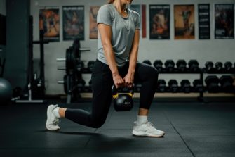 Close up shot of man at, gym holding dark supplement shaker. 