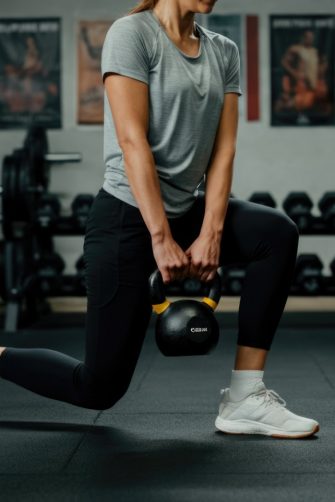 Close up shot of man at, gym holding dark supplement shaker. 