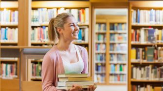 Couple smiling at each other at the library while holding books