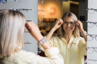 Photograph of a science student holding glasses and facing a mirror