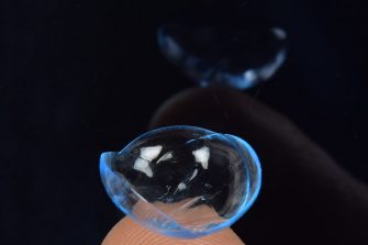 Contact lens on finger with dark background