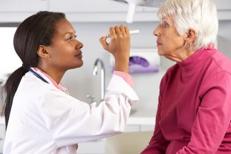 Female Doctor Examining Senior Female Patient's Eyes