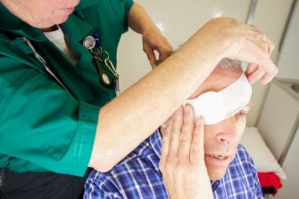 Paramedic nurse bandaging a patient's eye after injury- drops applied bandages being wrapped.