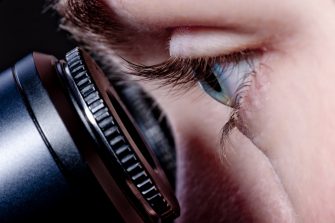 Closeup of eye looking down a microscope