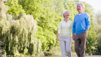 Older couple walking beside a river holding hands