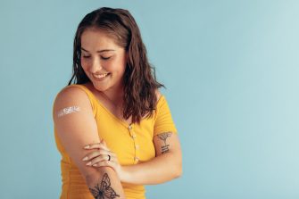 Woman looking at her arm with band-aid after receiving vaccine dose. 
