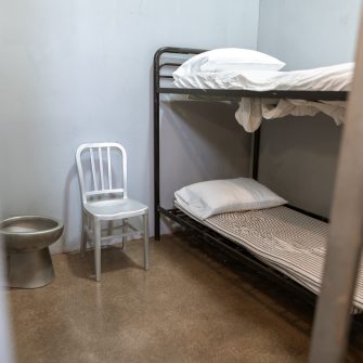 A Bunk Bed With Striped Foam Mattress in a Prison Cell