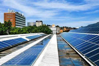 Rooftop solar panels in the foreground with UNSW Library in the background against blue sky