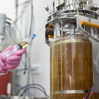 RPF laboratory detail photo of someone adding liquid to a fermenter tank