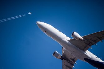 plane in flight with blue skies and another plane in the distance