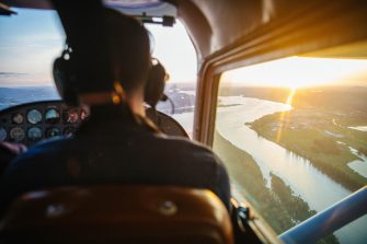 View from inside a helicopter cockpit flying over a river