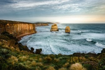 Rock formations on sea under cloudy sky