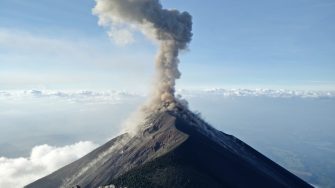 Smoking volcano with clouds and in the background