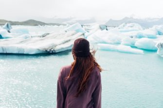 Woman wearing purple shirt overlooking a body of water and snow covered field