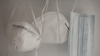 Three masks hanging on hooks on a wall