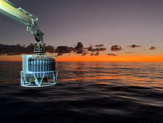 Equipment being lowered into the ocean at sunrise