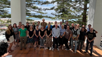 The Our Future Oceans team gathered on a balcony with a beach behind them. Located in Wollongong.