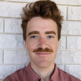 image of man smiling at camera brick behind