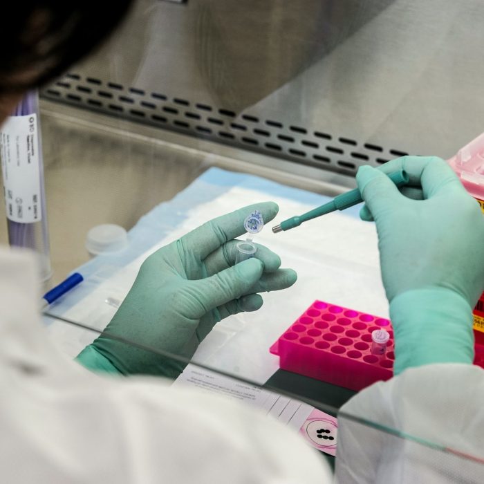 Close of gloved hands performing scientific experiment