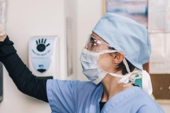 Woman in scrubs getting medical supplies from a shelf